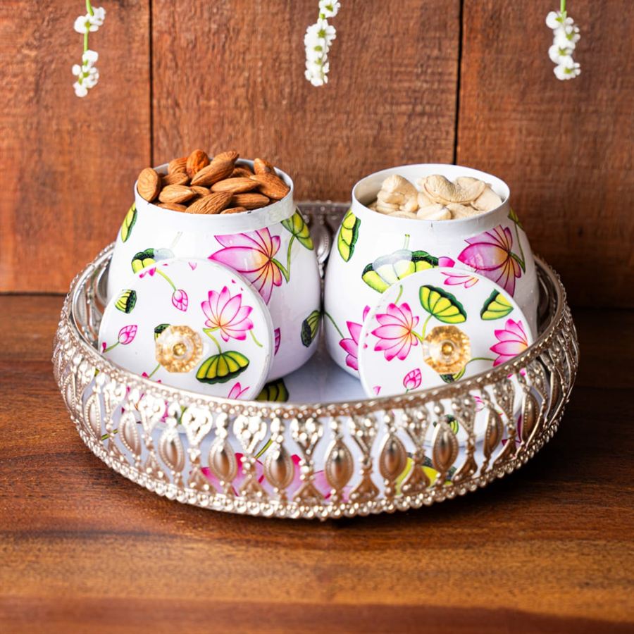 Two hand-painted lotus jars filled with almonds and cashews on a silver tray